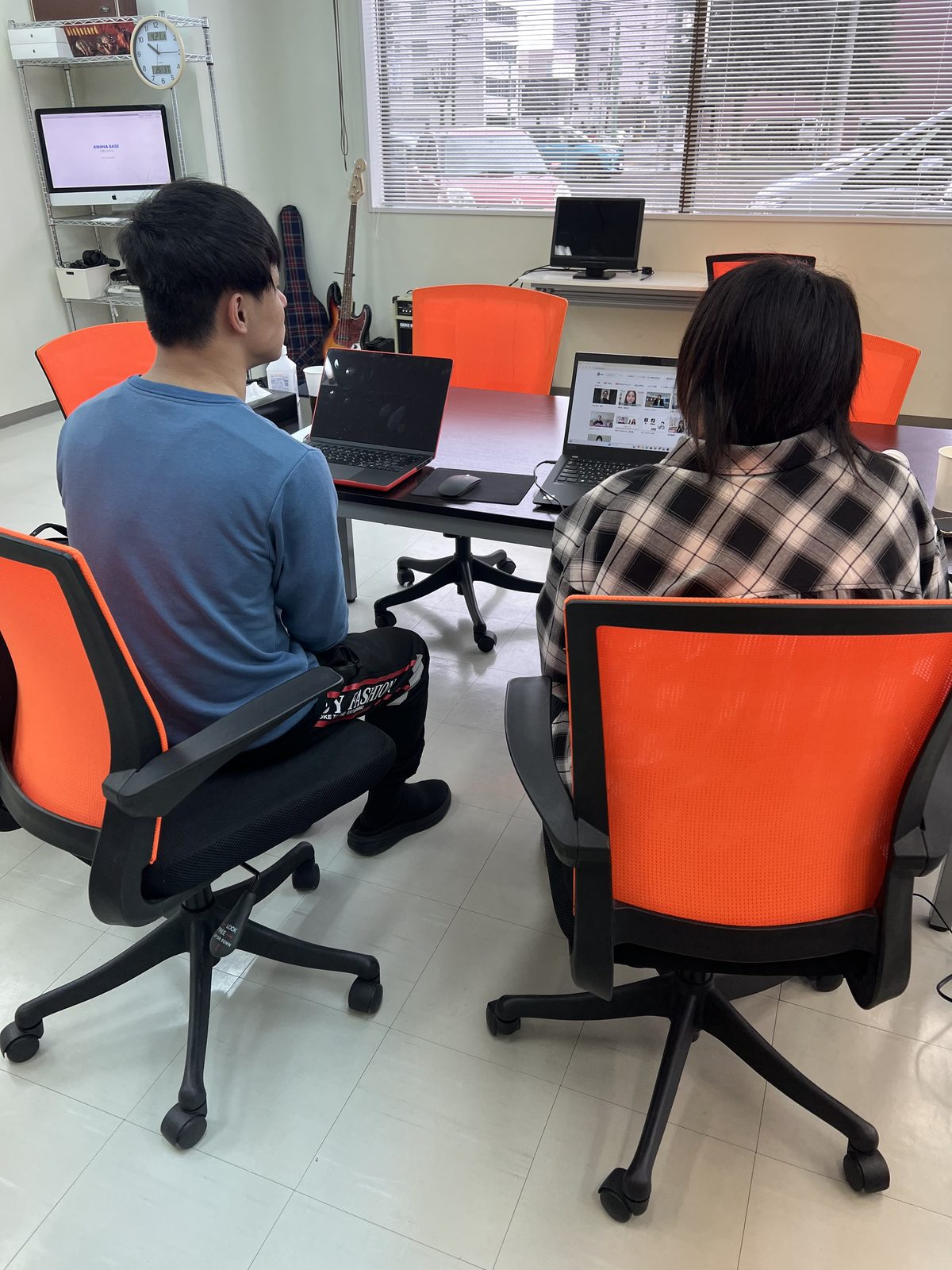 オレンジのチェアに座り、ノートパソコンで作業する2人の利用者さん